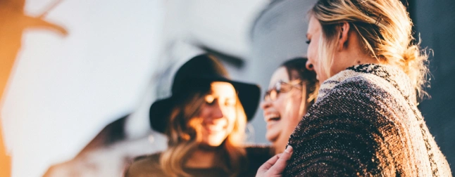 life coaching Relationships Three people, likely women, are smiling and interacting closely, suggesting a positive social connection.